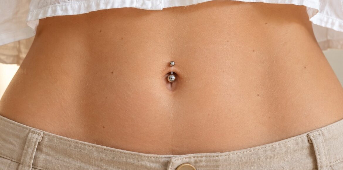 Navel piercing με απλή ασημί καμπύλη μπάρα στο επάνω χείλος του αφαλού