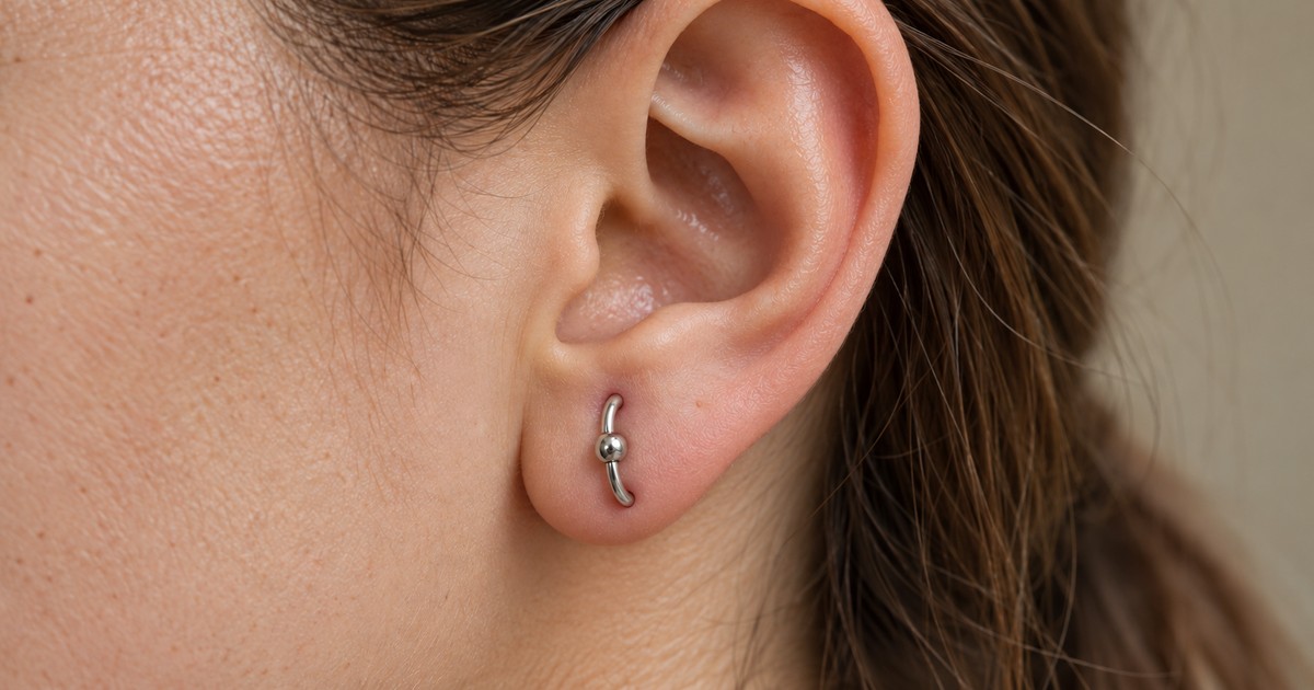 Ενδεικτικό orbital piercing στον λοβό με έναν ασημί κρίκο που συνδέει δύο διατρήσεις
